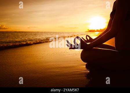 Frau am Strand bei Sonnenuntergang zu meditieren. Stockfoto