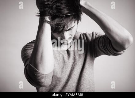 Erschöpfter, besorgter junger asiatischer Mann. Stockfoto