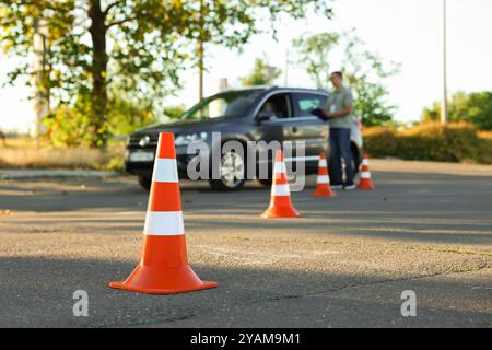 Der Prüfer, der den Schüler vor der Prüfung auf der Fahrschule anweist, konzentriert sich auf den Verkehrskegel Stockfoto