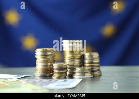 Stapel von Münzen und Euro-Banknoten auf grauem Tisch Stockfoto