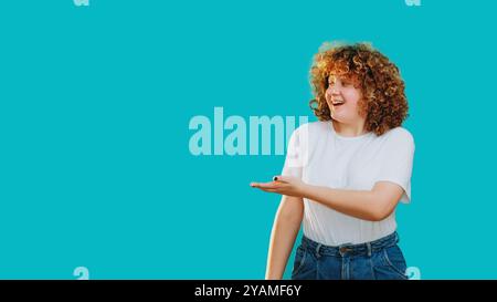 Fröhliche Frau lächelt Punkte, die positive Energie Enthusiasmus ausstrahlen, isoliert auf blauem leeren Raum Hintergrund. Stockfoto