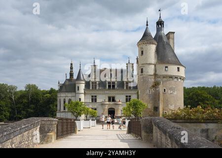 Imposante Burg mit Turm und Besuchern auf der Brücke vor einem bewölkten Himmel, Chenonceau Castle, Chateau de Chenonceau, Wasserschloss, Cher River, Stockfoto