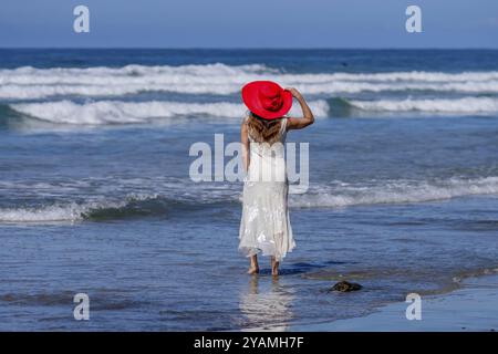 Atemberaubende Frau sonnt sich in der Nähe eines Piers, unter klarem blauem Himmel und genießt die Ruhe eines perfekten Tages am Meer Stockfoto