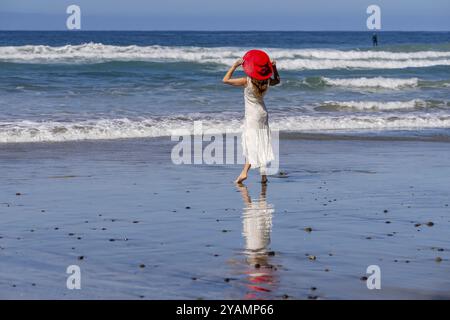 Atemberaubende Frau sonnt sich in der Nähe eines Piers, unter klarem blauem Himmel und genießt die Ruhe eines perfekten Tages am Meer Stockfoto