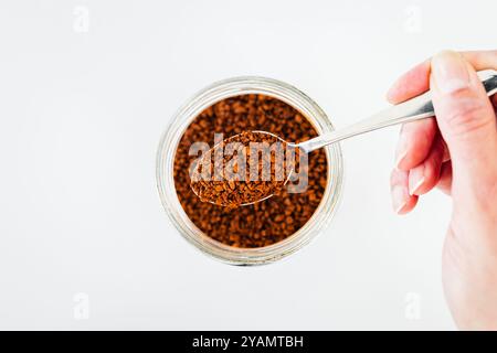 Nahaufnahme der Vorratskammer, Löffel Instantkaffee über klarem Glas, Schuss von oben, tägliche Zutaten Stockfoto