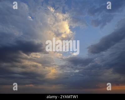 Blick auf den Himmel mit dramatischen Wolken während Sonnenuntergang nach dem Sturm. Das Sonnenlicht blickt hindurch und schafft eine atemberaubende und stimmungsvolle Wolkenlandschaft mit Stockfoto