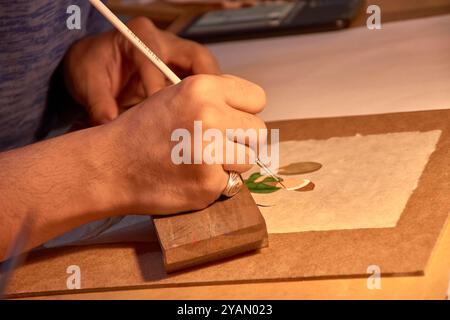 Dieses fesselnde Bild zeigt die geschickten Hände einer handwerklichen Holzmalerei auf einem der pulsierenden Basare von Buchara, Usbekistan. Bekannt für sein reiches Cu Stockfoto