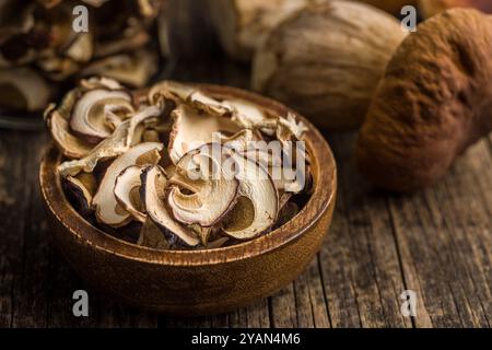 Getrocknete Stachelpilze. Geschnittener Boletus in Holzschale auf einem Holztisch. Stockfoto