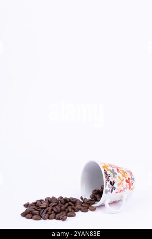 Eine gemütliche Szene mit einer warmen Tasse Kaffee und einem Haufen Kaffeebohnen auf einer hellweißen Oberfläche Stockfoto