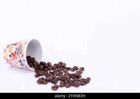 Eine perfekt gebrühte Tasse Kaffee neben einem großzügigen Stapel Kaffeebohnen auf einem makellos weißen Hintergrund Stockfoto