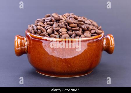 Eine Dampfschale mit frisch gerösteten Kaffeebohnen ist einladend und zeigt ihre reichhaltige Textur und ihr tiefes Aroma vor einem eleganten schwarzen Hintergrund Stockfoto