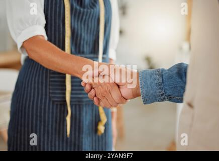 Kreativ, Handschlag und Diskussion mit Kunden, Abschluss und Vereinbarung in Werkstatt, Modedesigner und Schürze. Schneiderei, Hände halten und Leute in sich Stockfoto