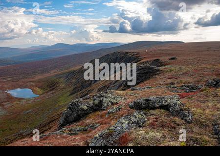 Zwei Wanderer bestaunen den atemberaubenden panoramablick auf eine weitläufige Bergkette mit einem ruhigen See im Tal darunter Stockfoto