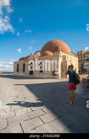 Der Mann allein reist, Rückansicht eines Mannes, der ein Foto der Kucuk Hasan Pascha Moschee im Hafen der Altstadt von Chania (Hania) auf Kreta, Griechenland, macht Stockfoto