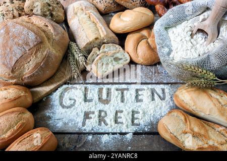 Frisch gebackenes glutenfreies Brotsortiment auf dunklem rustikalem Hintergrund. Text Glutenfrei ist handgeschrieben in Mehl. Konzept für gesunde Ernährung Stockfoto