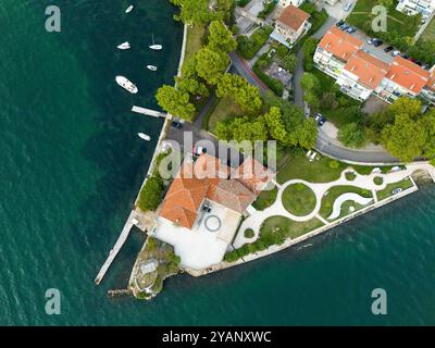 Ein Damm, der ins Meer ragt, mit Häusern, Parkplätzen und geparkten Booten. Luftaufnahme Stockfoto