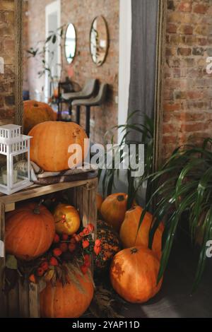 Thanksgiving-Einrichtung mit Herbstkürbissen und Gemüse auf rustikalem Hintergrund. Details zum Stillleben. Herbstdekor, getrocknete Blumen, Kerze, Kürbis Stockfoto