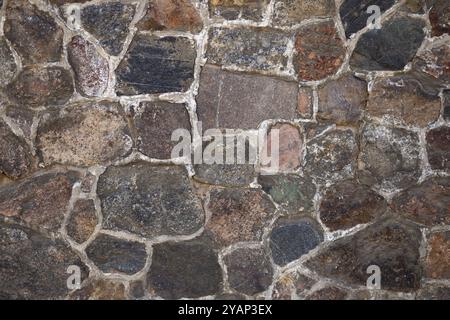 Nahaufnahme einer rustikalen Steinmauer mit unregelmäßigen Formen und natürlicher Textur bei Tageslicht. Konzept für Architektur, Konstruktion und Außenbereich Stockfoto