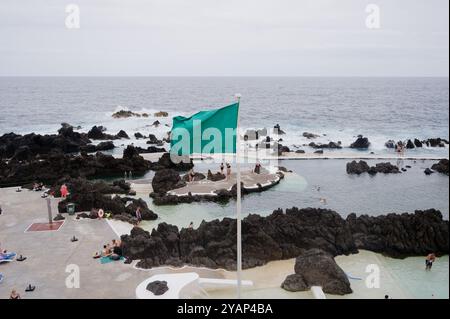 Grüne Flagge, die als Schwimmer die natürlichen Pools von Porto Moniz genießen Stockfoto