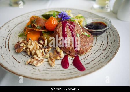 Veganer Gourmet-Burger serviert mit Walnüssen, Gemüse, essbaren Blumen und einer lebendigen roten Rübensauce Stockfoto