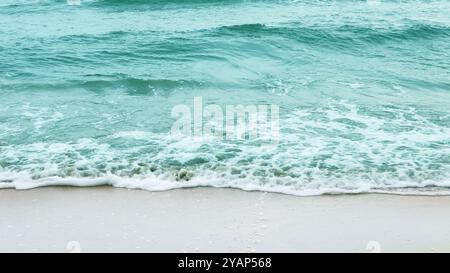 Atemberaubende Aussicht auf azurblaue Meereswellen, die sanft auf einen unberührten Sandstrand stürzen und ein Gefühl der Entspannung und Flucht wecken. Das Bild vermittelt die Idee o Stockfoto