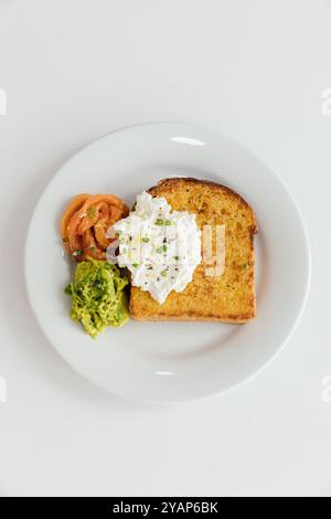 Ein weißer Teller mit Toast, Guacamole und Schlagsahne darauf Stockfoto