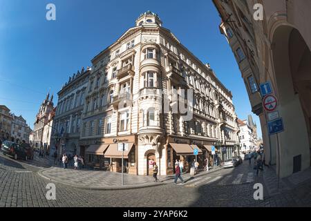 Prag, Tschechische Republik - 18. Mai 2017: Menschen laufen auf einer Kopfsteinpflasterstraße in Prag, Tschechische Republik, vorbei an traditionellen Gebäuden und Geschäften Stockfoto