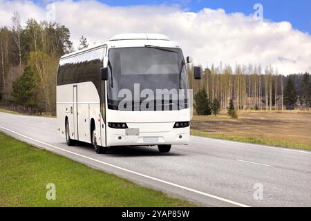 Der weiße Bus befördert Passagiere an einem schönen Frühlingstag auf der Autobahn. Stockfoto