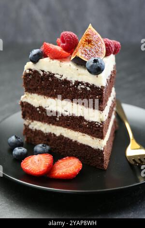 Ein Stück leckerer Schokoladen-Biskuitkuchen mit Beeren auf dem Tisch, Nahaufnahme Stockfoto