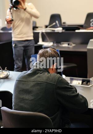 Hamburg, Deutschland. Oktober 2024. Ein 34-jähriger Mann (Front), der wegen Mordes und besonders schwerer Brandstiftung angeklagt ist, wartet im Gerichtssaal auf den Beginn des Prozesses. Der Angeklagte soll das Opfer mehrmals im Kopf- und Halsbereich mit einem Messer erstochen haben. Der Angriff führte zum Tod des Mannes. Danach soll der Angeklagte die Wohnung angezündet haben, um das Verbrechen zu vertuschen. Quelle: Ulrich Perrey/dpa/Alamy Live News Stockfoto