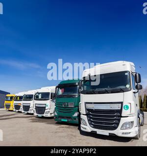 Nutzfahrzeug für den geschäftlichen Transport. Mehrere Sattelauflieger sind hintereinander geparkt. Zehn Radlaster parkten an sonnigem Tag gegen die SK Stockfoto