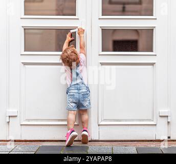 Ein Kind versucht, eine Tür auf der Straße zu öffnen. Stockfoto