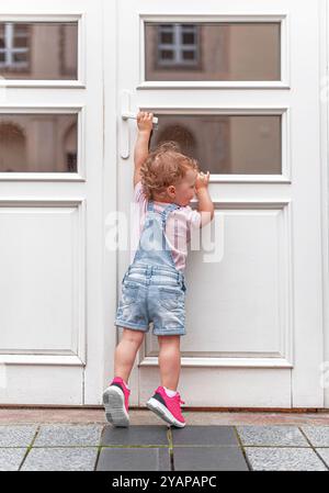 Ein Kind versucht, eine Tür auf der Straße zu öffnen. Stockfoto