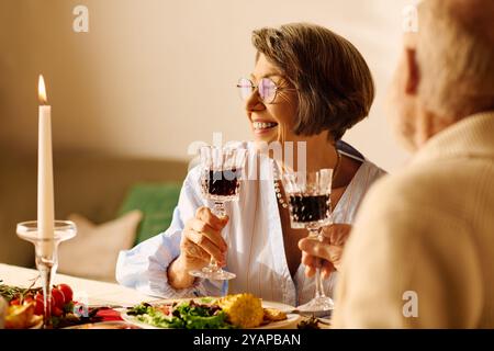 Ein fröhliches Seniorenpaar genießt ein festliches Abendessen zusammen und hebt die Brille zur Feier. Stockfoto