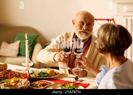 Ein älteres Paar genießt einen herzlichen Toast während ihrer gemütlichen Weihnachtsfeier zu Hause. Stockfoto