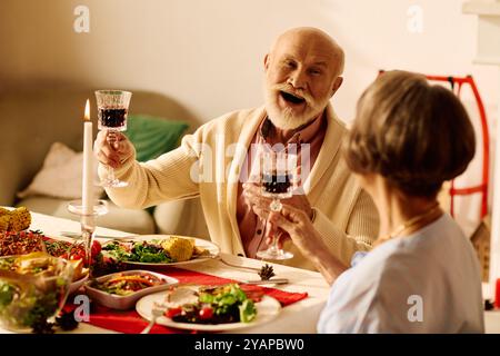 Ein Seniorenpaar hebt bei einem gemütlichen Weihnachtsessen zu Hause die Gläser auf. Stockfoto