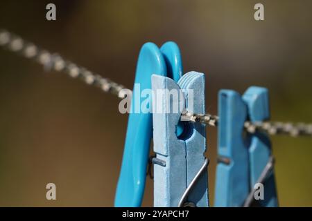 Nahaufnahme eines blauen Kleiderschranks, der an einem Seil befestigt ist, hält einen täglichen Outdoor-Moment mit einem Hauch von Minimalismus fest. Stockfoto
