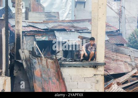 Manila, Philippinen. Oktober 2024. Ein Bewohner kehrt nach einem Brand in einem Slum-Gebiet in Manila, den Philippinen, am 15. Oktober 2024 in sein verkohltes Haus zurück. Quelle: Rouelle Umali/Xinhua/Alamy Live News Stockfoto