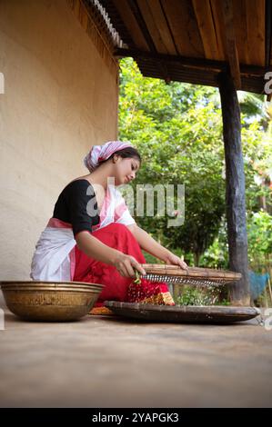 Ein assamesisches Mädchen trennt eifrig Schale von Reis mit einer traditionellen Dola und Saloni, wodurch das zeitlose Erbe ihres Dorfes bewahrt wird. Stockfoto