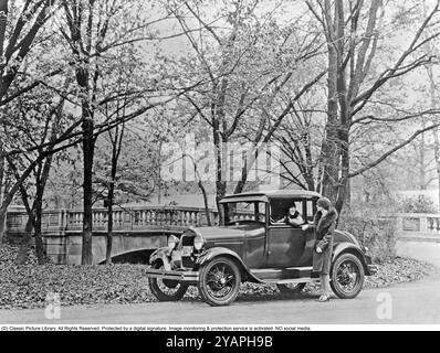 Das alte Ford-Auto. Ein Ford Model A Cabriolet 1927 mit zwei Frauen in der typischen jahrzehntelangen Mode. Das Modell war mit einem dickflüssigen Sitz im Heck ausgestattet, der, wenn er ausgeklappt wurde, einen zusätzlichen Sitz öffnete. Stockfoto