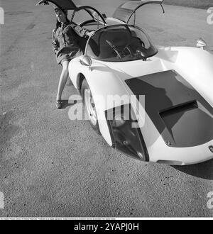 Porsche Juni 1967. Ein Modell, das auf einem Porsche 906 in der Mode des Jahres gekleidet ist. Das Rennwagenmodell wurde 1966 auf den Markt gebracht und wird auch Porsche Carrera 6 genannt. Das Auto hatte Autotüren, genannt GullFlügeltüren, eine Art von Autotür, die sich nach oben öffnet. Insgesamt wurden 50 Exemplare des Autos produziert, die unter anderem vom schwedischen Rennfahrer Sten Axelsson im Motorsport eingesetzt wurden. Foto mit Hasselblad Stockfoto