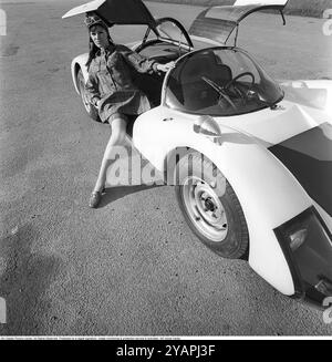 Porsche Juni 1967. Ein Modell, das auf einem Porsche 906 in der Mode des Jahres gekleidet ist. Das Rennwagenmodell wurde 1966 auf den Markt gebracht und wird auch Porsche Carrera 6 genannt. Das Auto hatte Autotüren, genannt GullFlügeltüren, eine Art von Autotür, die sich nach oben öffnet. Insgesamt wurden 50 Exemplare des Autos produziert, die unter anderem vom schwedischen Rennfahrer Sten Axelsson im Motorsport eingesetzt wurden. Foto mit Hasselblad Stockfoto