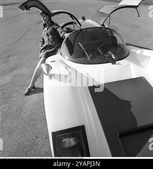 Porsche Juni 1967. Ein Modell, das auf einem Porsche 906 in der Mode des Jahres gekleidet ist. Das Rennwagenmodell wurde 1966 auf den Markt gebracht und wird auch Porsche Carrera 6 genannt. Das Auto hatte Autotüren, genannt GullFlügeltüren, eine Art von Autotür, die sich nach oben öffnet. Insgesamt wurden 50 Exemplare des Autos produziert, die unter anderem vom schwedischen Rennfahrer Sten Axelsson im Motorsport eingesetzt wurden. Foto mit Hasselblad Stockfoto