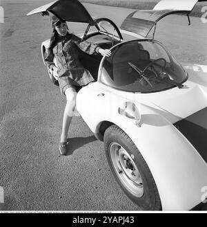 Porsche Juni 1967. Ein Modell, das auf einem Porsche 906 in der Mode des Jahres gekleidet ist. Das Rennwagenmodell wurde 1966 auf den Markt gebracht und wird auch Porsche Carrera 6 genannt. Das Auto hatte Autotüren, genannt GullFlügeltüren, eine Art von Autotür, die sich nach oben öffnet. Insgesamt wurden 50 Exemplare des Autos produziert, die unter anderem vom schwedischen Rennfahrer Sten Axelsson im Motorsport eingesetzt wurden. Foto mit Hasselblad Stockfoto