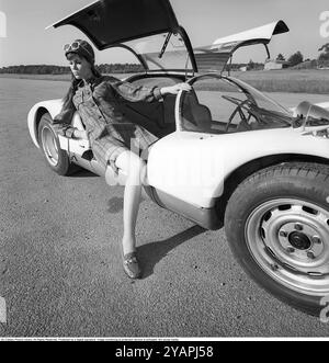 Porsche Juni 1967. Ein Modell, das auf einem Porsche 906 in der Mode des Jahres gekleidet ist. Das Rennwagenmodell wurde 1966 auf den Markt gebracht und wird auch Porsche Carrera 6 genannt. Das Auto hatte Autotüren, genannt GullFlügeltüren, eine Art von Autotür, die sich nach oben öffnet. Insgesamt wurden 50 Exemplare des Autos produziert, die unter anderem vom schwedischen Rennfahrer Sten Axelsson im Motorsport eingesetzt wurden. Foto mit Hasselblad Stockfoto