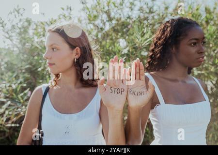 Zwei Frauen zeigen ihre Handflächen mit der Aufschrift „Stop Rassismus“ auf die Hände. Stockfoto