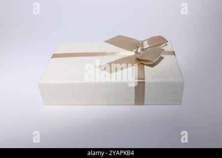 Beige Geschenkbox mit brauner Schleife, isoliert auf weißem Hintergrund. Stockfoto