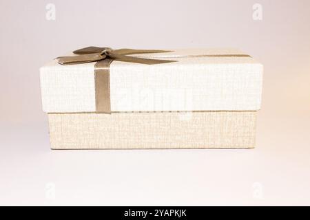 Beige Geschenkbox mit brauner Schleife, isoliert auf weißem Hintergrund. Stockfoto