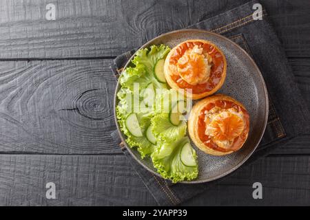 Mit Rindfleisch gefüllte french vol au Vent serviert mit Salat und Gurke in Nahaufnahme auf einem Teller auf einem Holztisch. Horizontale Draufsicht von oben Stockfoto