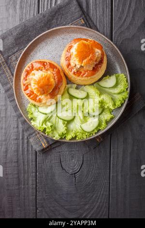 Blätterteig Bouchee oder vol-au-Vent mit Kalbsfleisch in scharfer Sauce serviert mit Salat und Gurke in Nahaufnahme auf einem Teller auf einem Holztisch. Vertikale Draufsicht Stockfoto